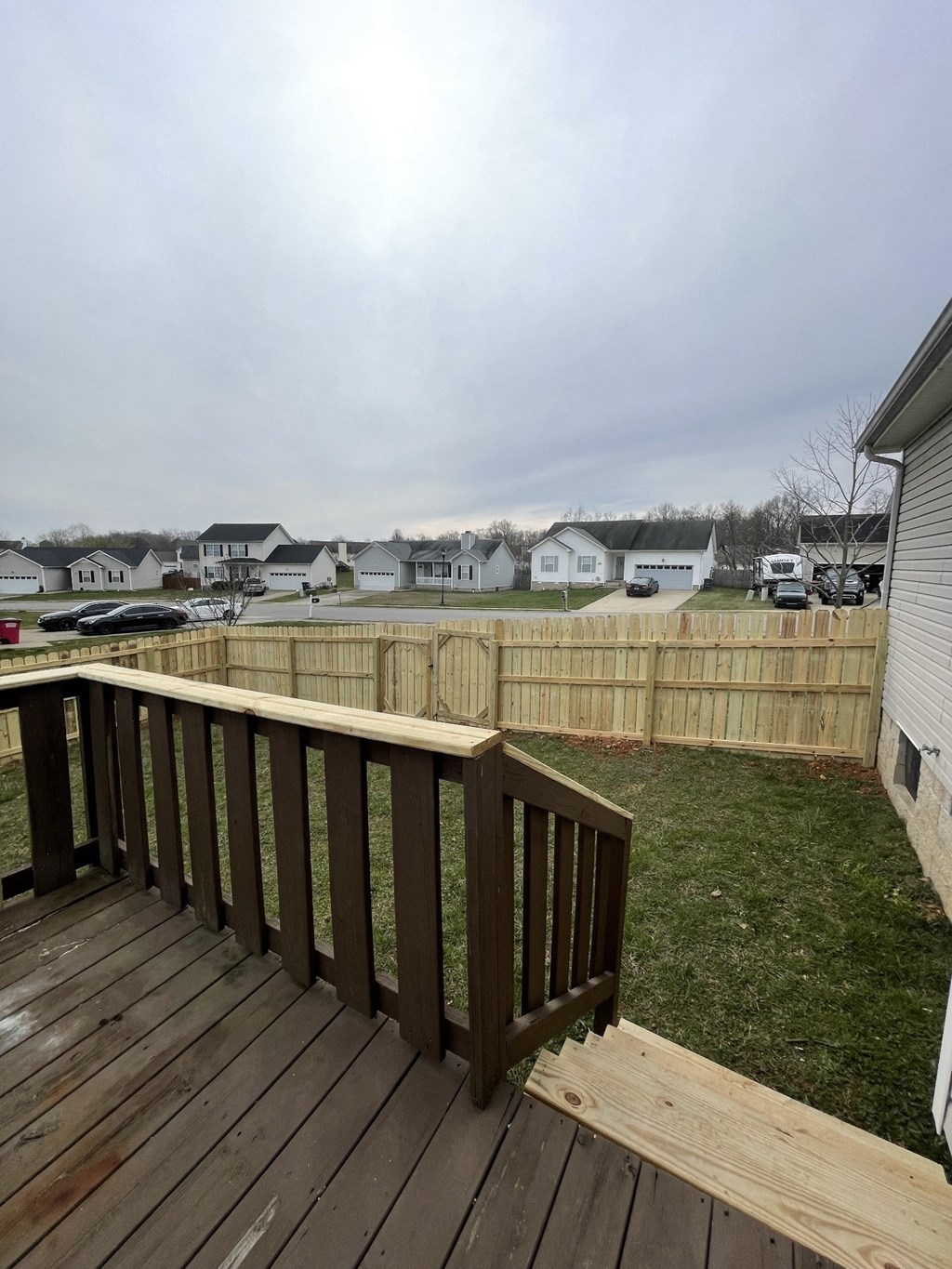 A wooden deck overlooks a grassy area with houses in the background.