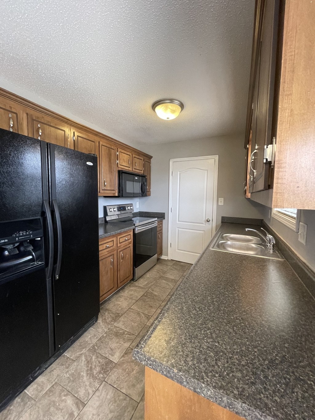 A black fridge in a kitchen with wooden cabinets.