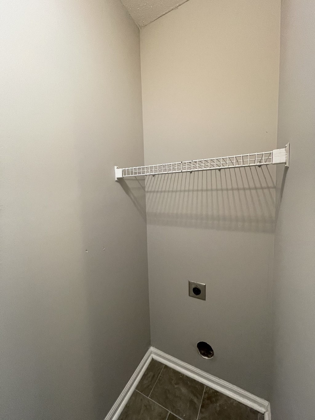 A white shelf in a corner of a bathroom.