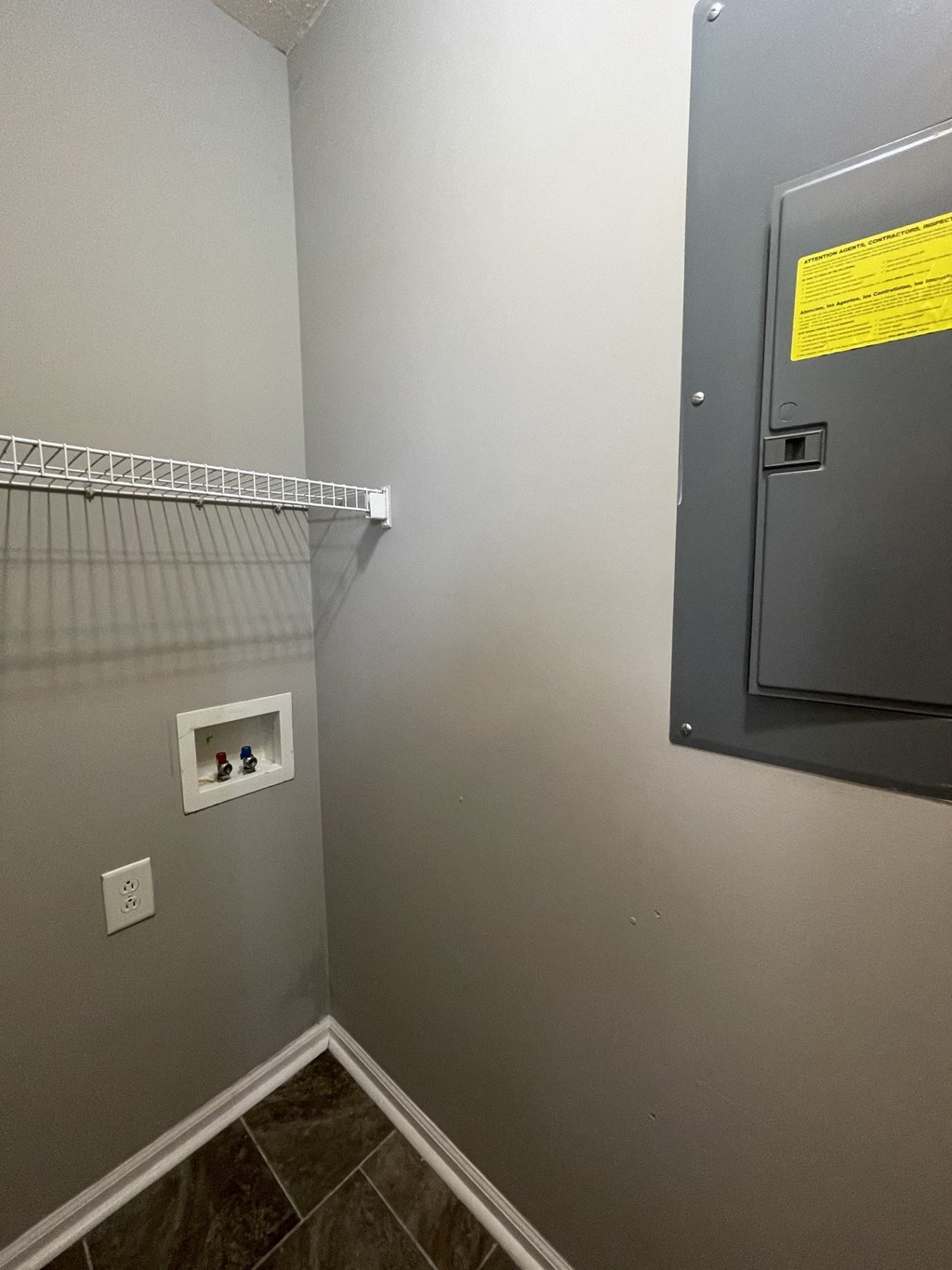 A bathroom with a grey wall and a yellow sign on the electrical box.