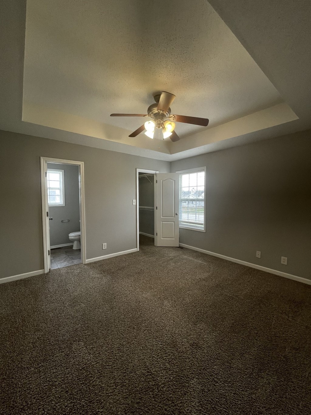 A room with a ceiling fan and carpeted floor.