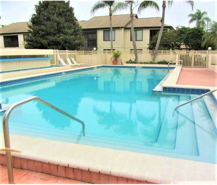 a large swimming pool with a house in the background
