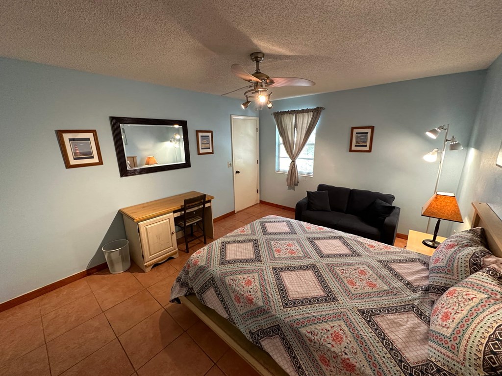 a bedroom with a bed and a chair and a ceiling fan