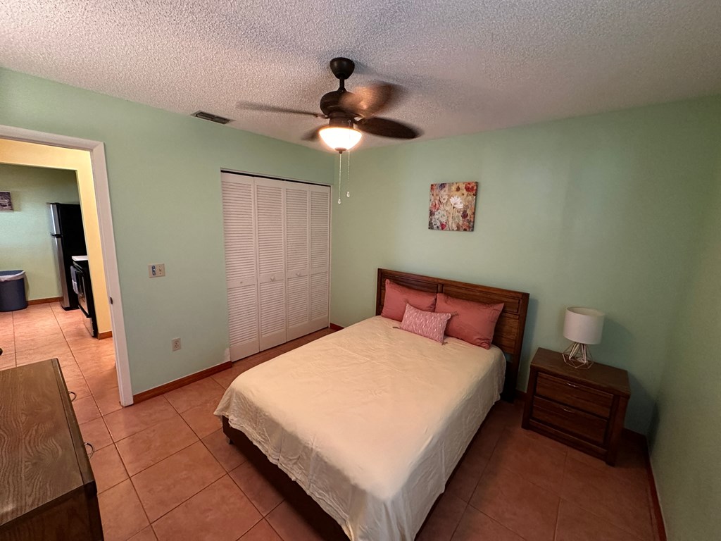 a bedroom with a white bed and a ceiling fan