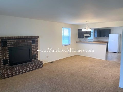 a large living room with a brick fireplace and a kitchen