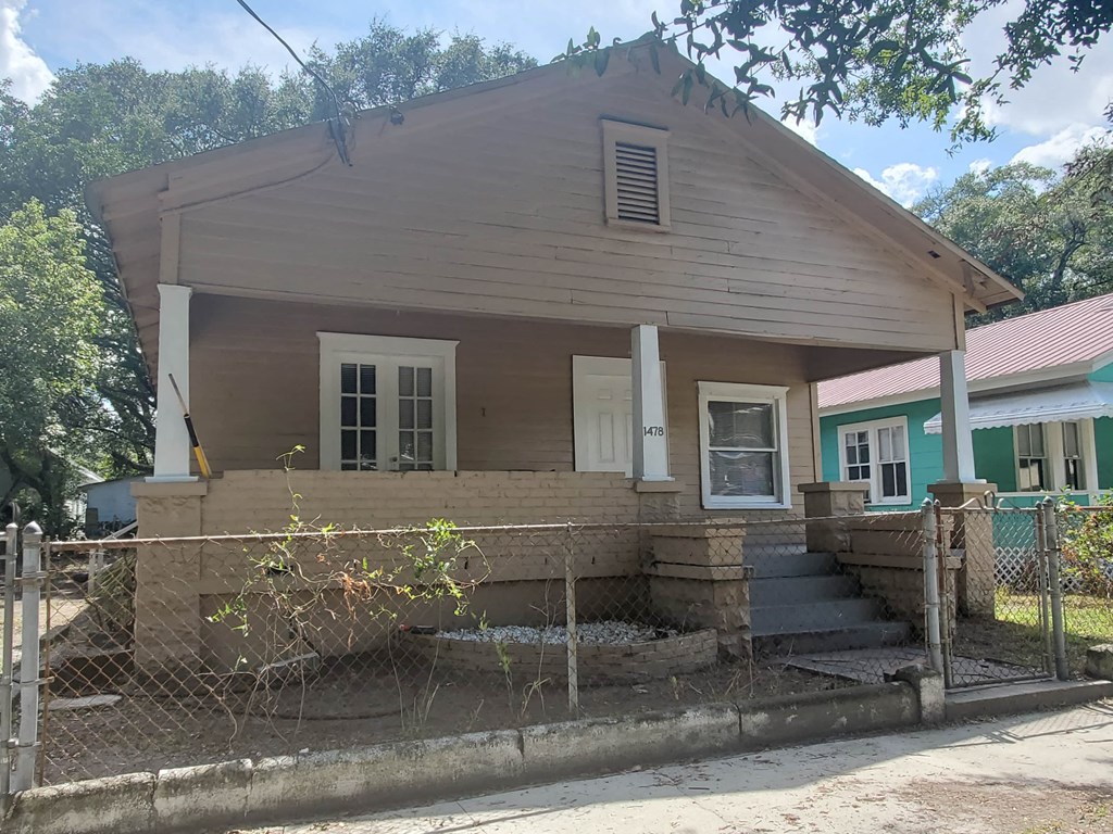 a small house with a fenced in porch and a fence