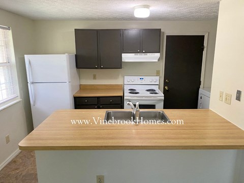 A kitchen with a white refrigerator, wooden countertop, and a stove top oven.