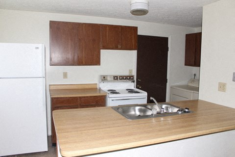 A kitchen with a white refrigerator and a wooden island with a sink.