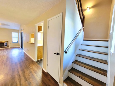 the entryway of a home with stairs and a door leading to a living room