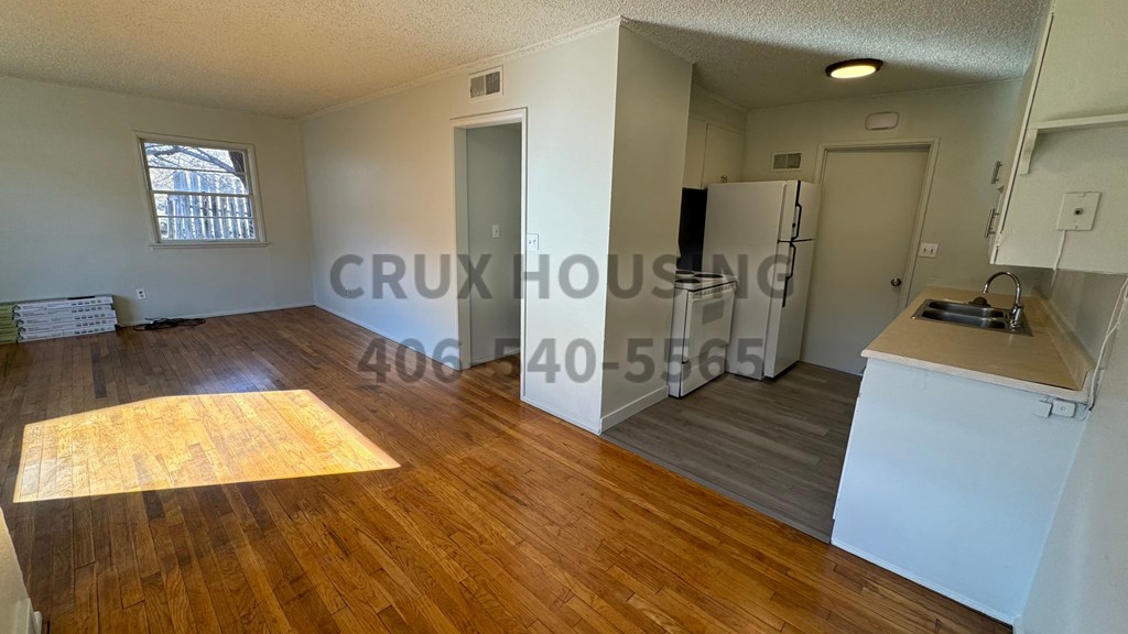 an empty living room and kitchen with a hard wood floor