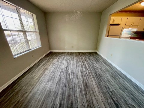 an empty living room with wooden floors and a window