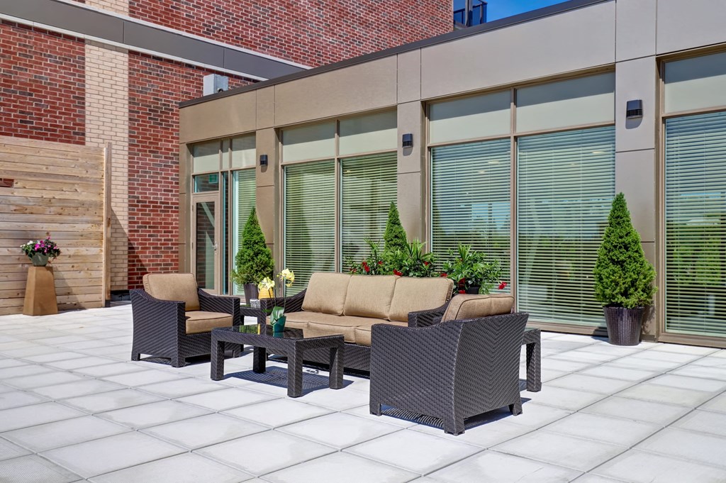 a patio outside of a building with furniture and plants