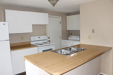 A kitchen with white appliances and wooden countertops.