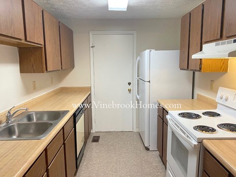 A kitchen with a white refrigerator, white stove, and brown cabinets.