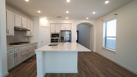 A kitchen with white cabinets and a large island in the middle.
