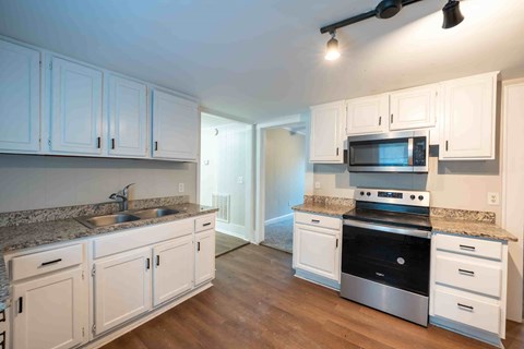 A kitchen with white cabinets and a granite countertop.