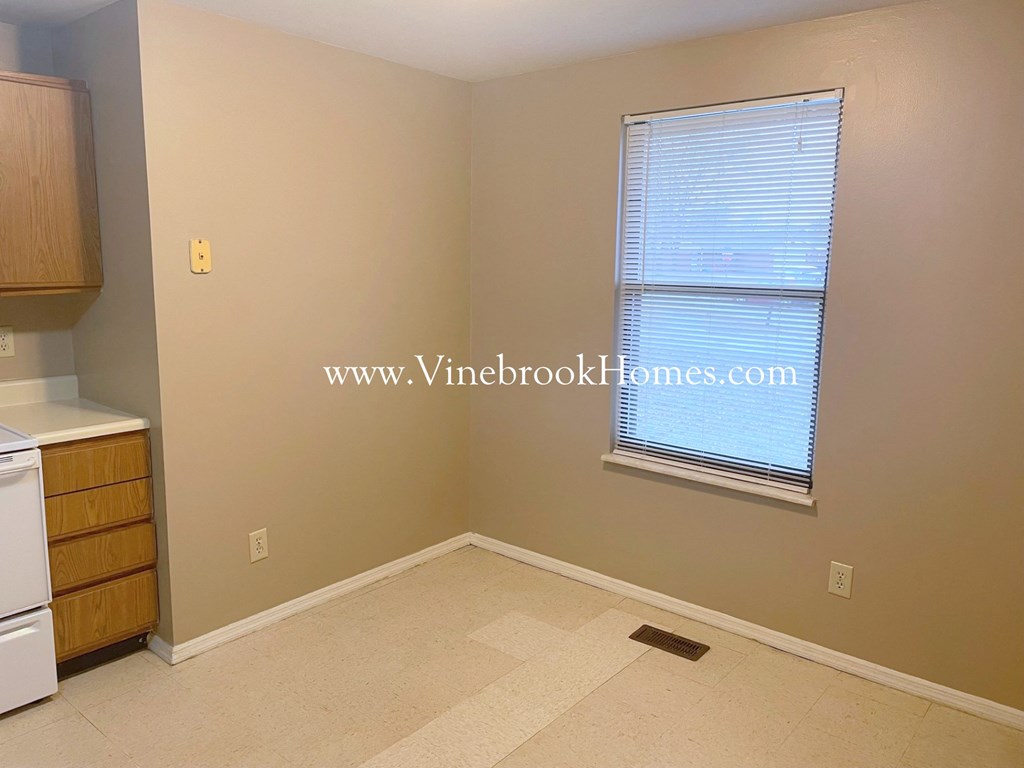 a small room with a window and a kitchen with wooden cabinets