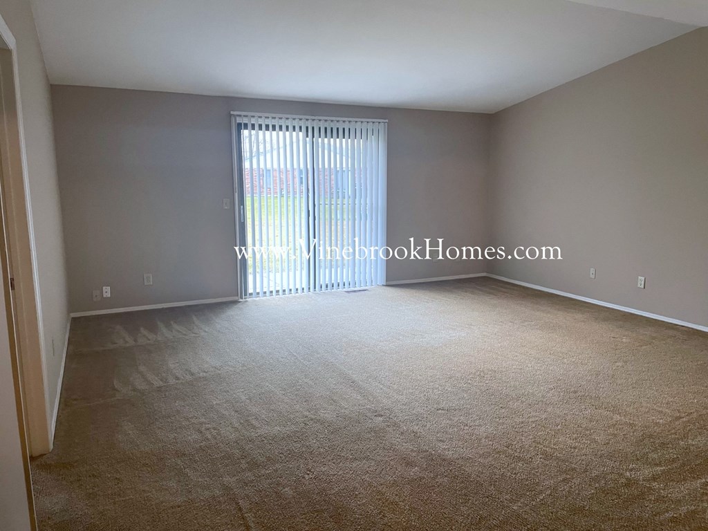 a living room with a large window and a carpeted floor