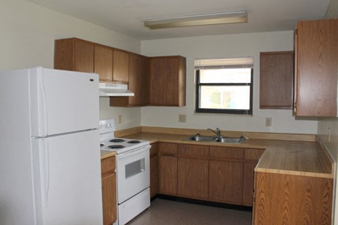 A kitchen with white appliances and wooden cabinets.