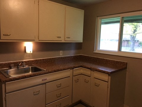 A kitchen with brown countertops and white cabinets.