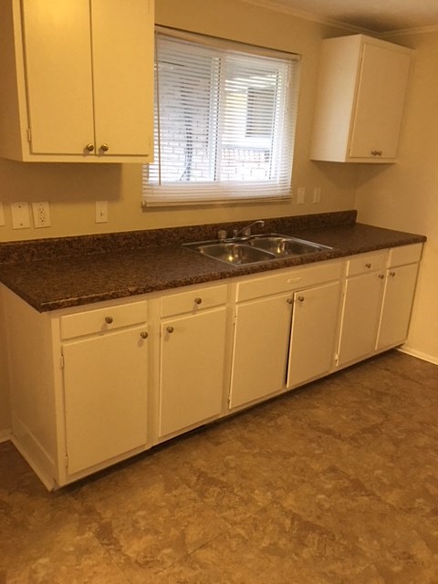 A kitchen with white cabinets and a granite countertop.
