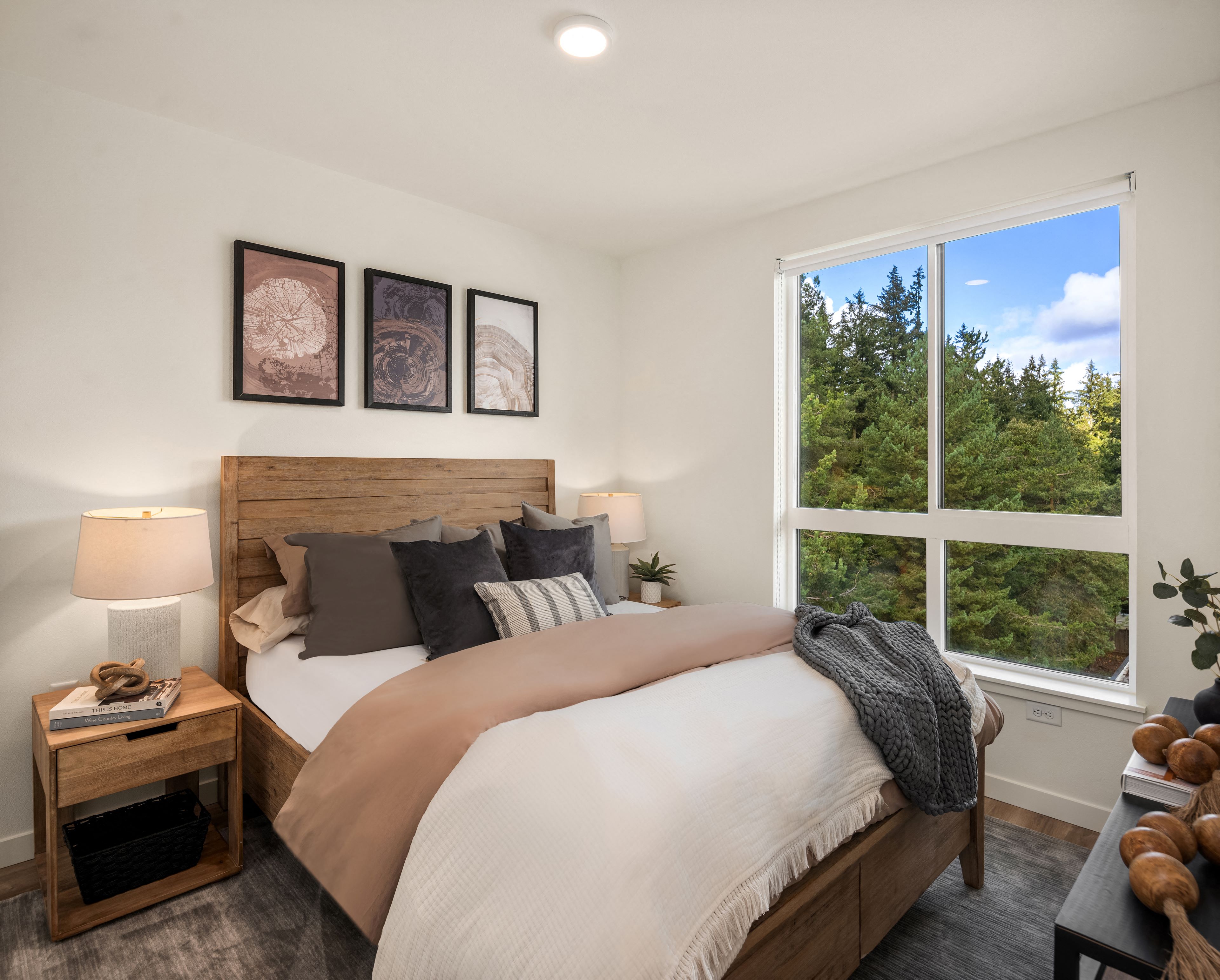 A bedroom with a large bed and a window overlooking a forest.