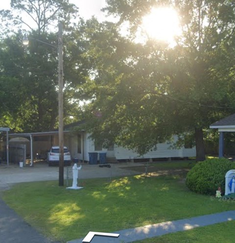 a yard with a white statue in front of a house