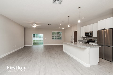 an open kitchen and living room with stainless steel appliances and a granite counter top