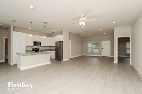 an open kitchen and living room with white cabinets and stainless steel appliances