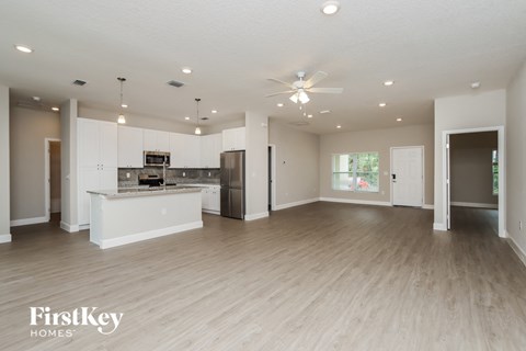 an open kitchen and living room with white cabinets and wood flooring
