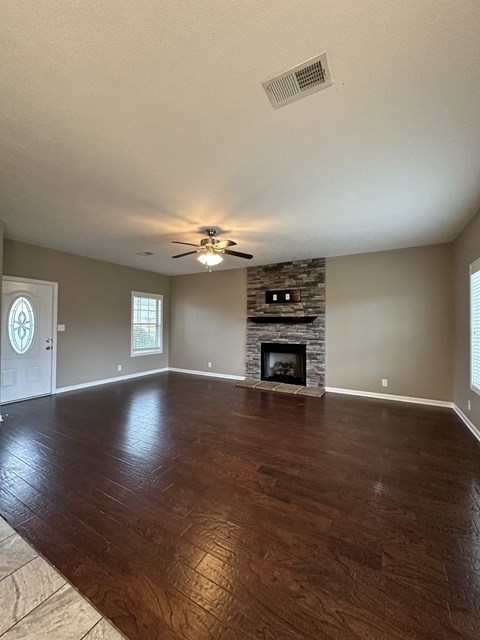 an empty living room with a fireplace and a ceiling fan