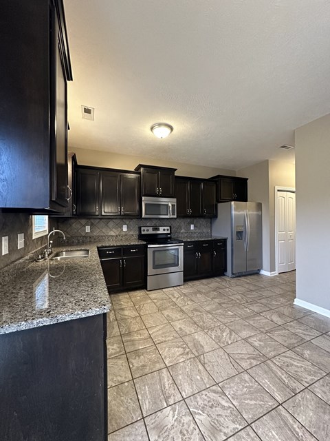 a kitchen with black cabinets and stainless steel appliances