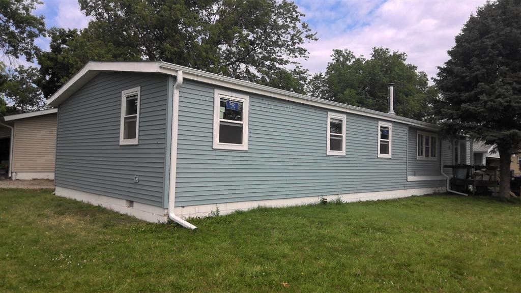 a blue house with a white roof and a lawn