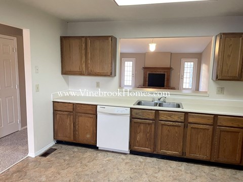 a kitchen with wooden cabinets and a white dishwasher and sink