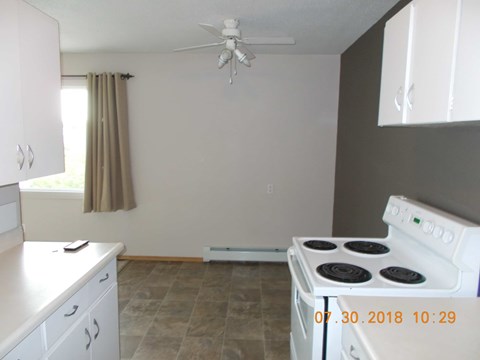 A kitchen with a white stove and a fan on the ceiling.
