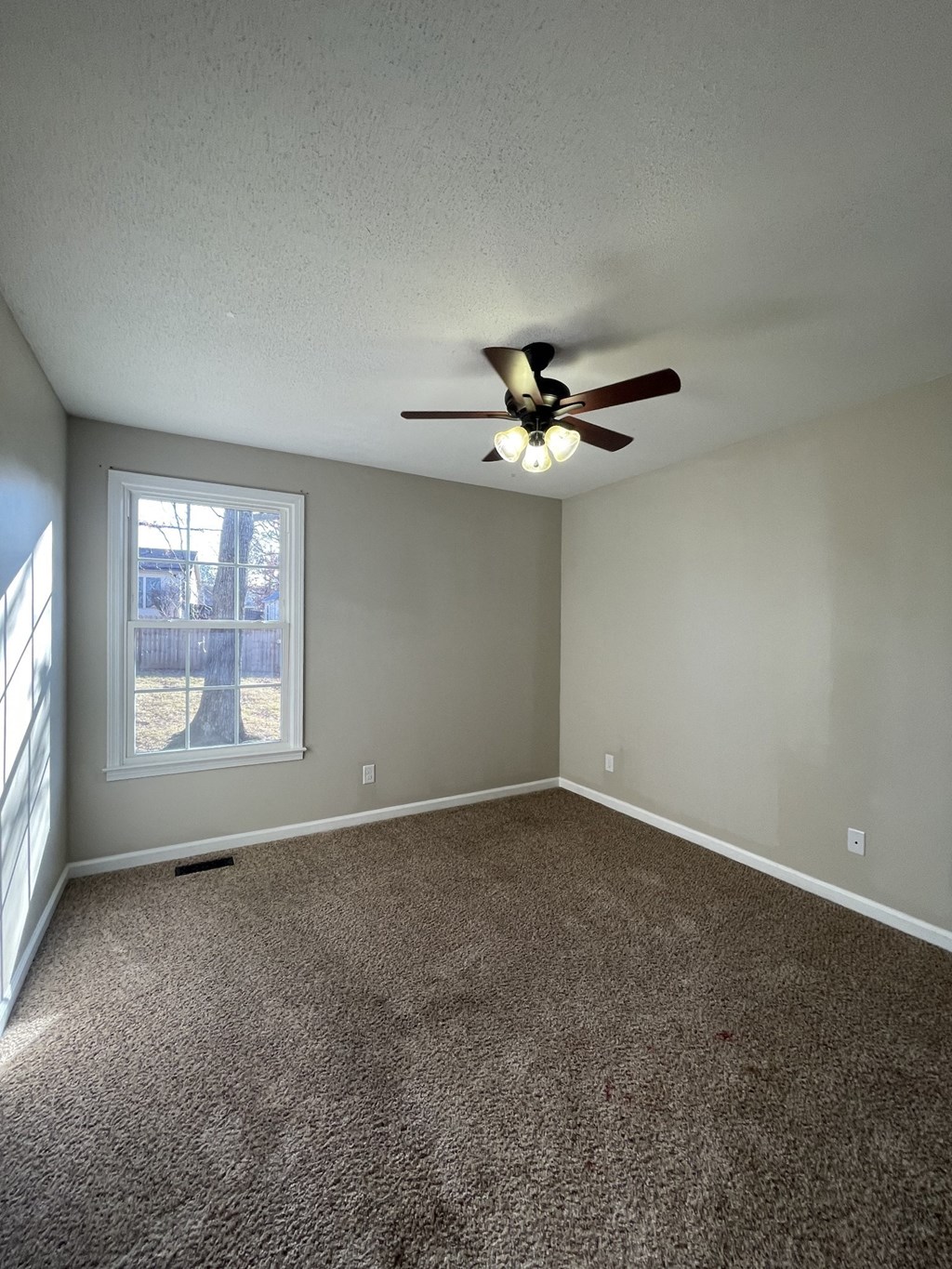 A room with a ceiling fan and carpeted floor.
