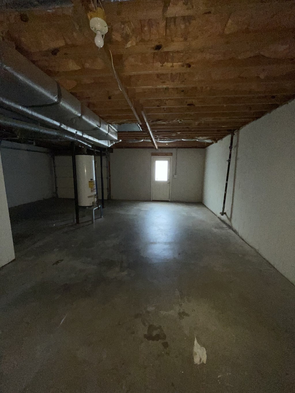 A room with a window and a door, and a pipe on the ceiling.