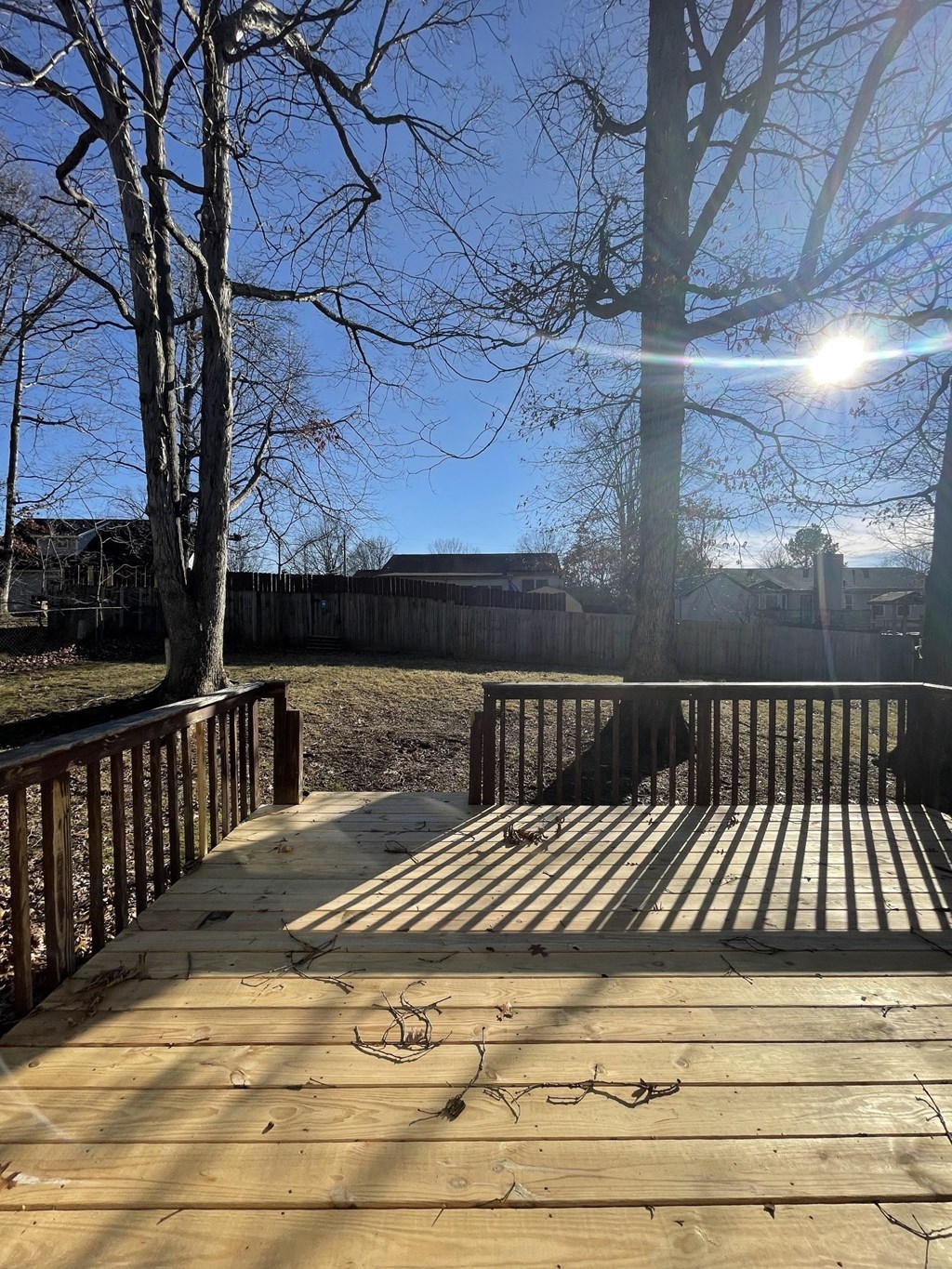 A wooden deck with a railing and a tree in the background.