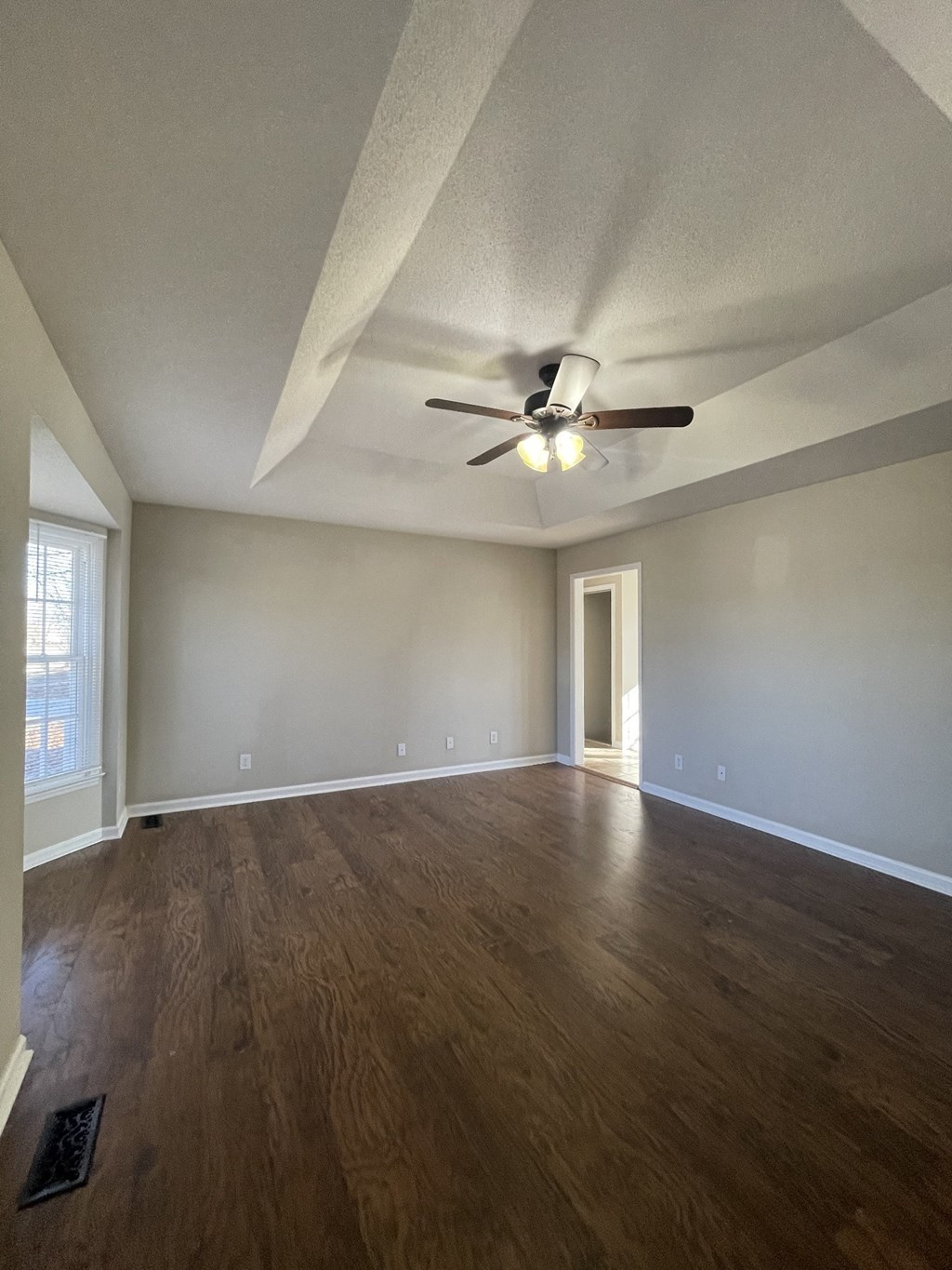 A room with a ceiling fan and wooden flooring.