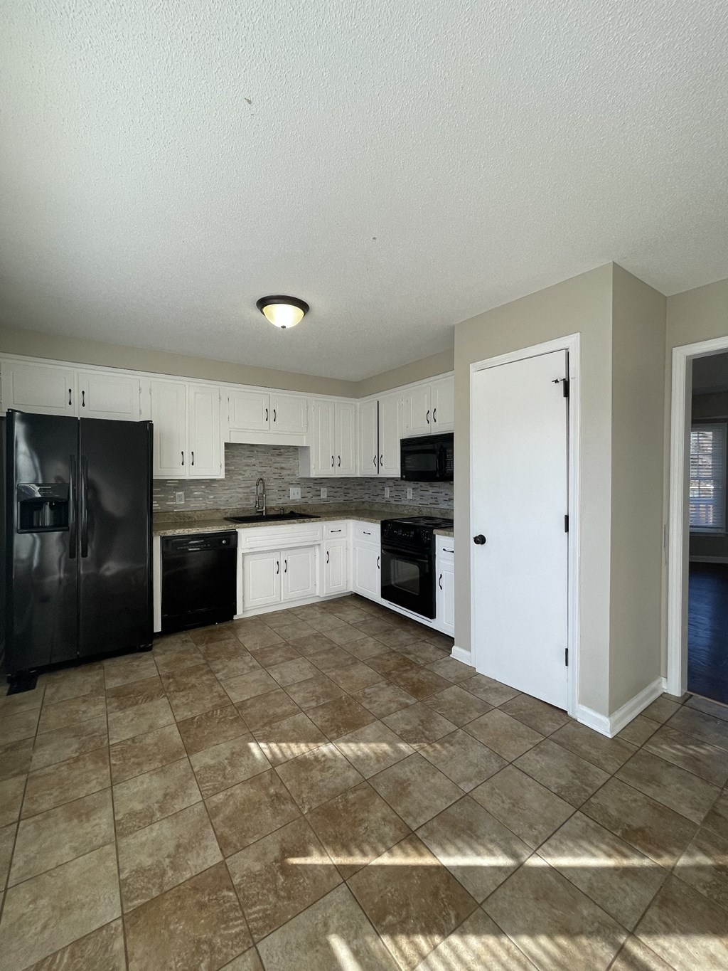 A kitchen with black appliances and white cabinets.