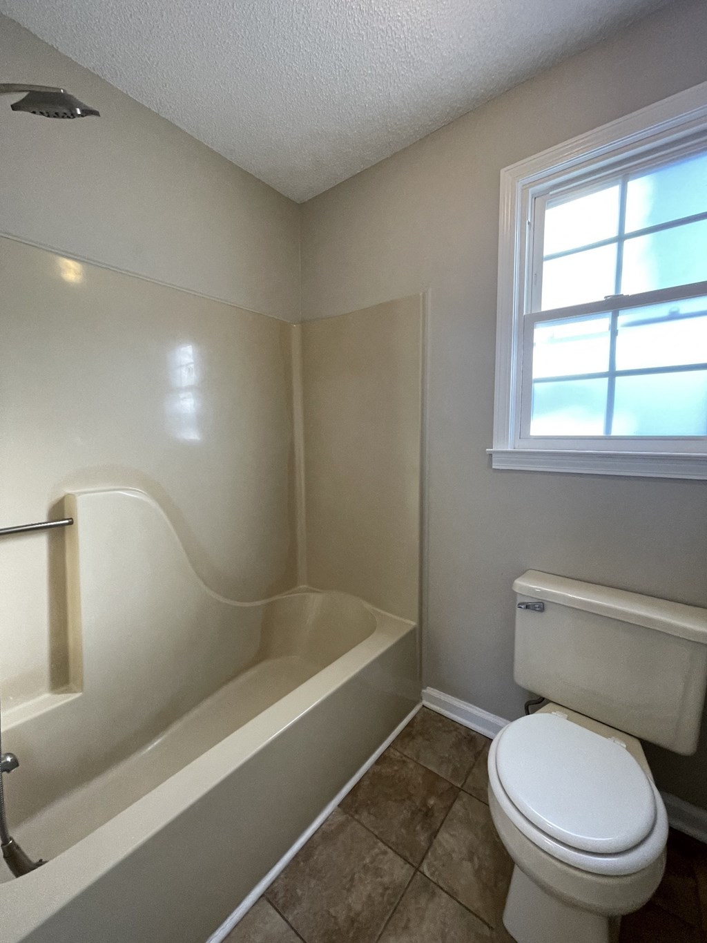A white toilet sits next to a bathtub in a bathroom.