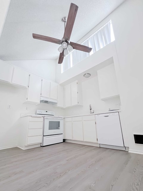 A white kitchen with a ceiling fan and a microwave oven.