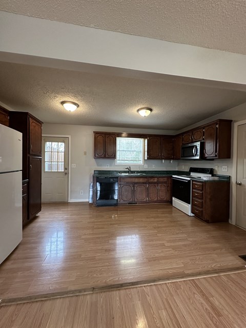 A kitchen with wooden floors and brown cabinets.