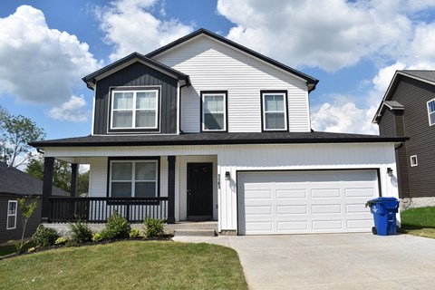 A two-story house with a black door and white garage door.