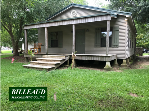 A house with a porch and a green lawn in front.