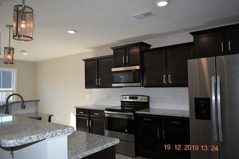 A kitchen with black cabinets and a marble countertop.