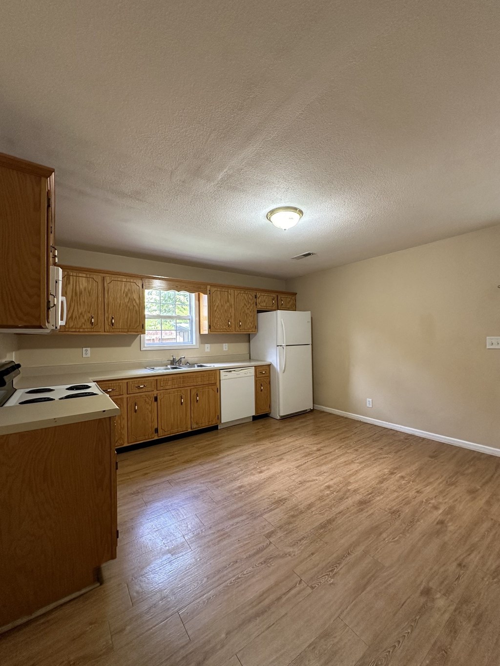 an empty kitchen with wooden cabinets and a stove and refrigerator