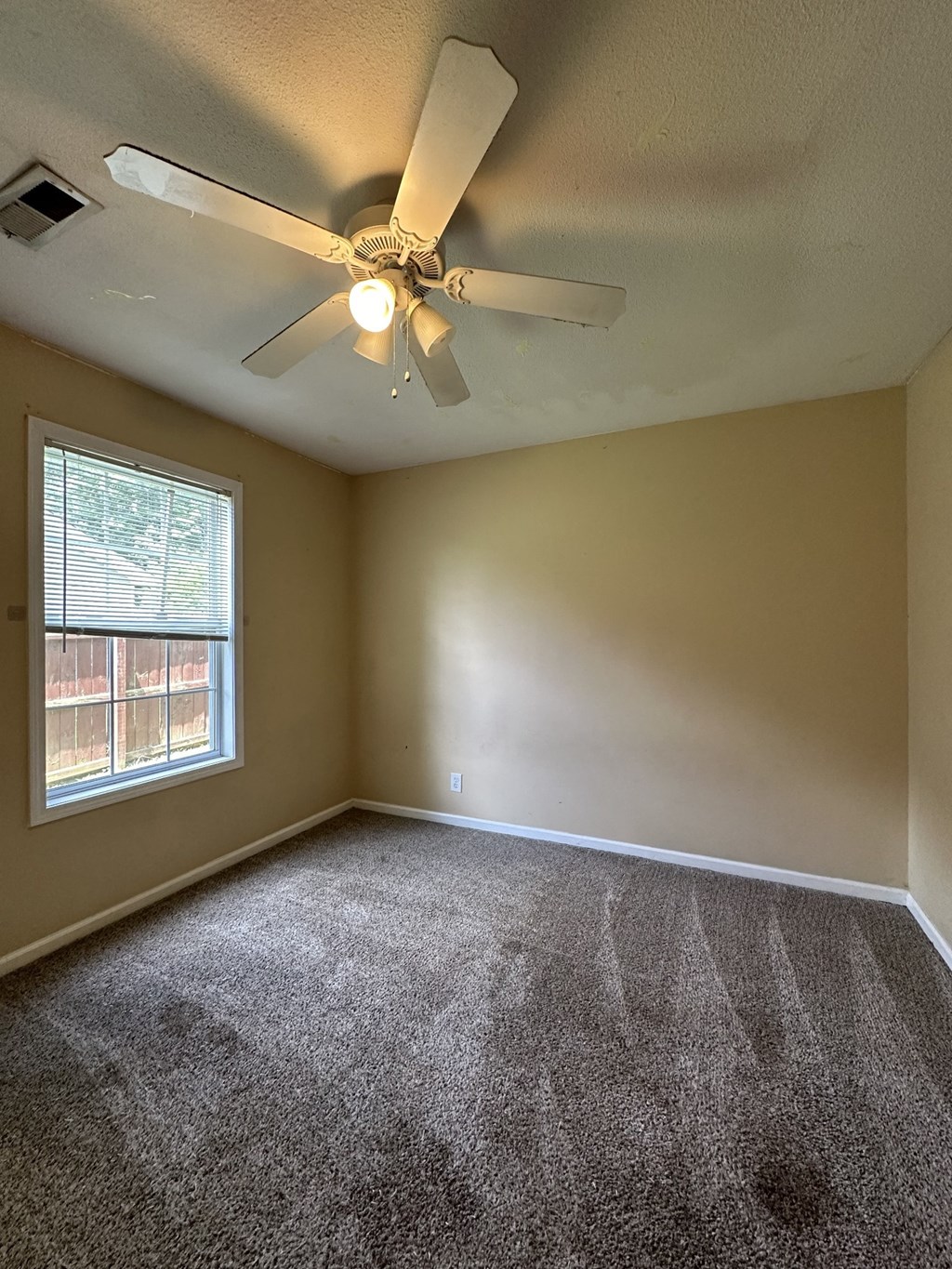 an empty living room with a ceiling fan and a window