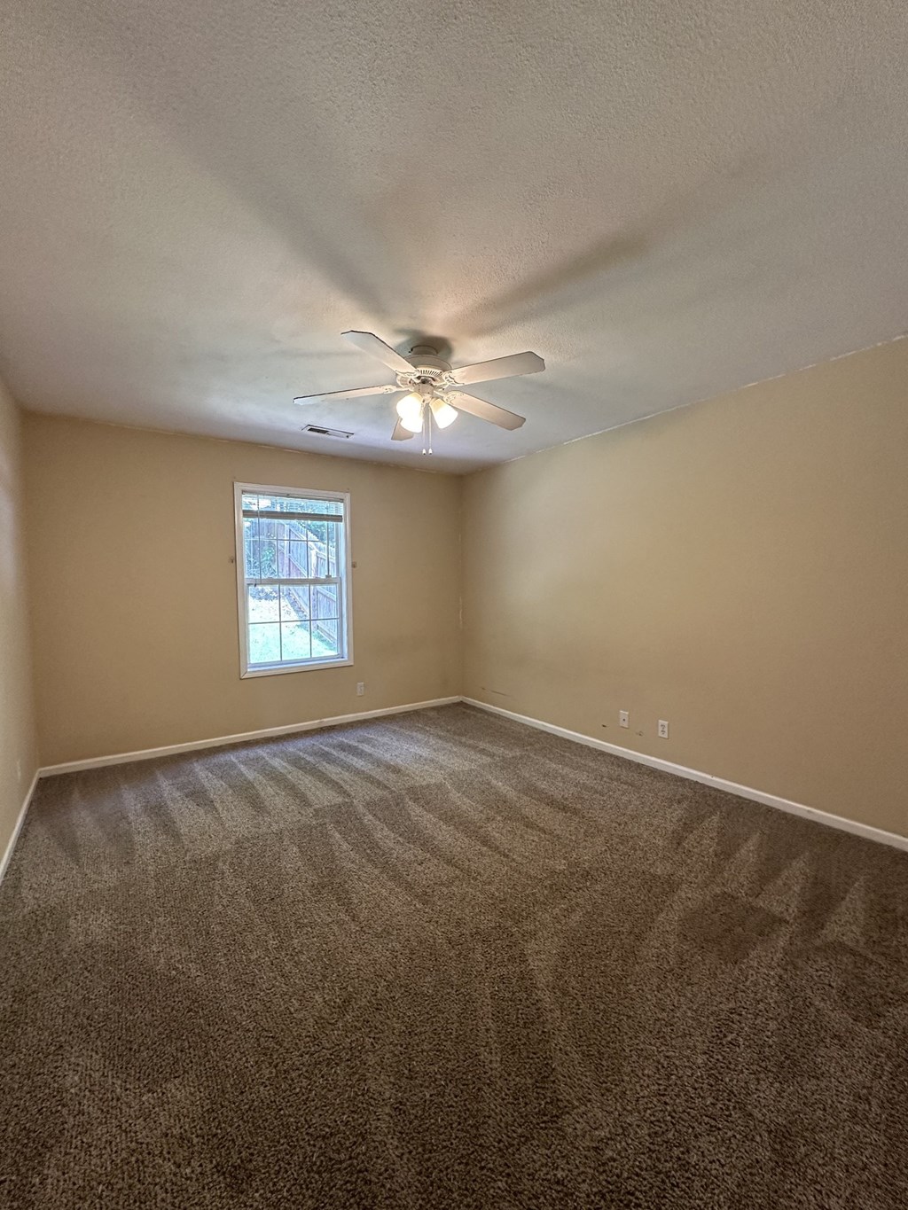 an empty living room with carpet and a ceiling fan