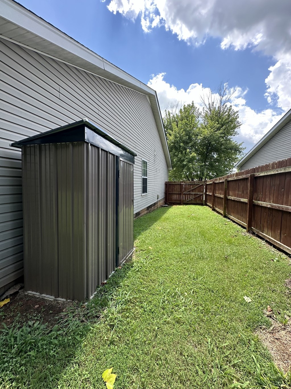 a backyard with a privacy fence and a shed on the side of a house